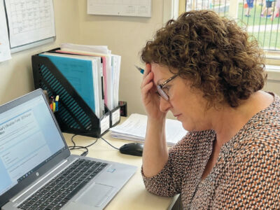 Childcare provider reviewing complex funding documents on her computer ahead of the BEEF grant deadline.