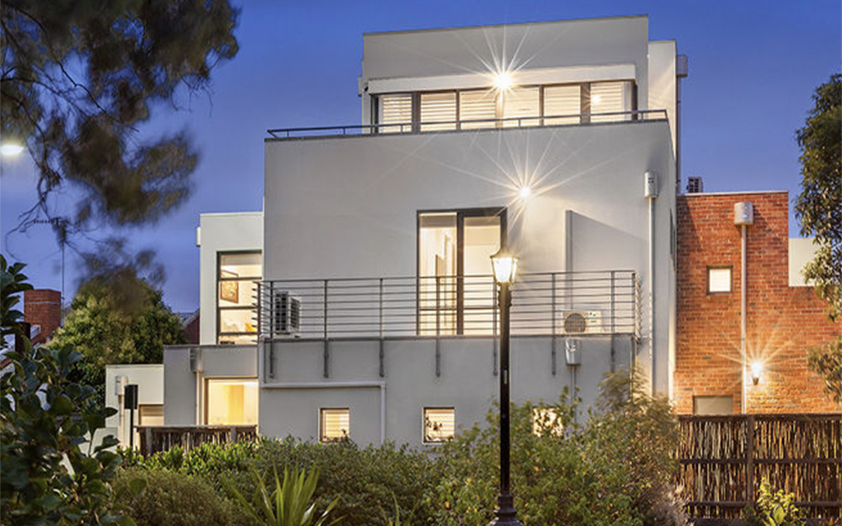 Contemporary townhouse exterior overlooking landscaped communal gardens at twilight.