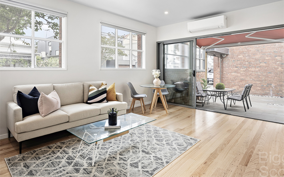 Open-plan living area with timber floors, air conditioning and seamless access to a private courtyard.