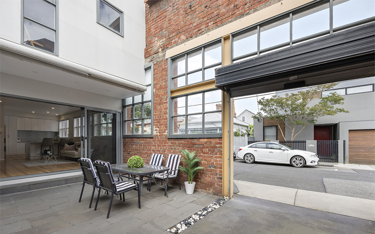 Private paved courtyard framed by restored red-brick warehouse walls and industrial-style windows.