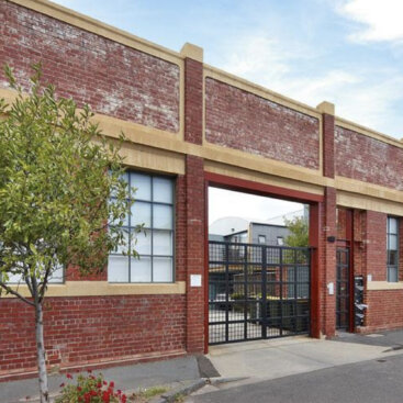 Restored heritage warehouse façade with secure gated entrance and original industrial brickwork.