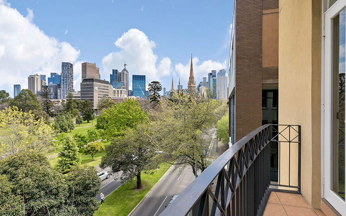 Balcony view from the Albert Street apartments overlooking Fitzroy Gardens and the Melbourne city skyline.