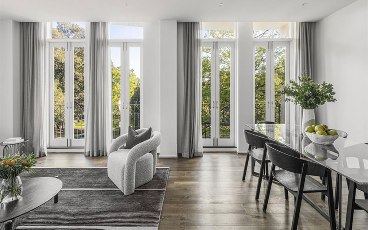 Open-plan apartment living and dining area with floor-to-ceiling windows at Albert Street, East Melbourne.