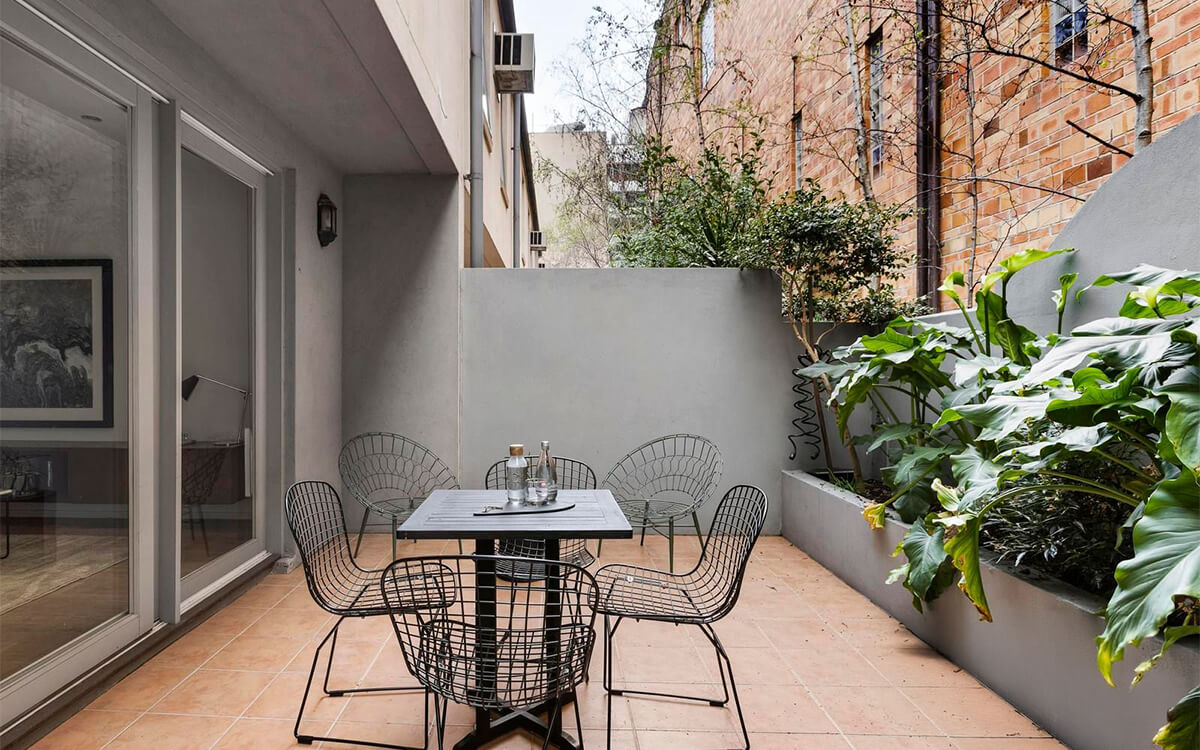Private ground-floor courtyard at the Albert Street apartments featuring outdoor seating and landscaped gardens.
