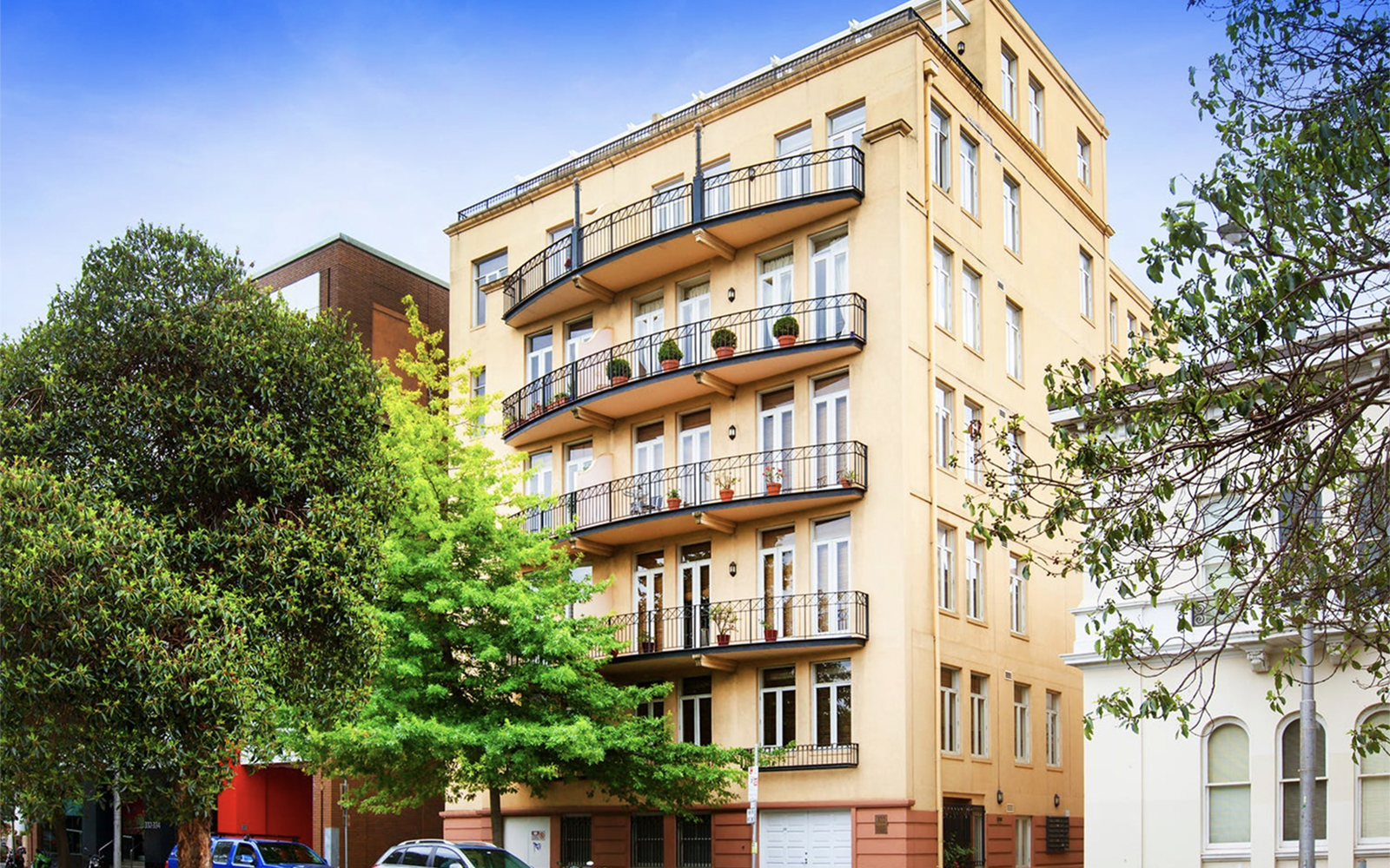 Residential apartment building on Albert Street, East Melbourne with balconies, heritage detailing and landscaped streetscape.
