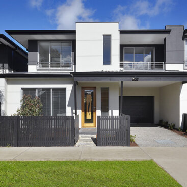 Front elevation of a two-storey townhouse with a fenced front yard, covered entry and attached garage.