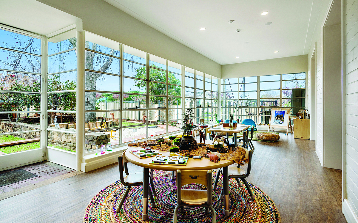 Children's learning space with activity tables, large windows and views to the outdoor play area.