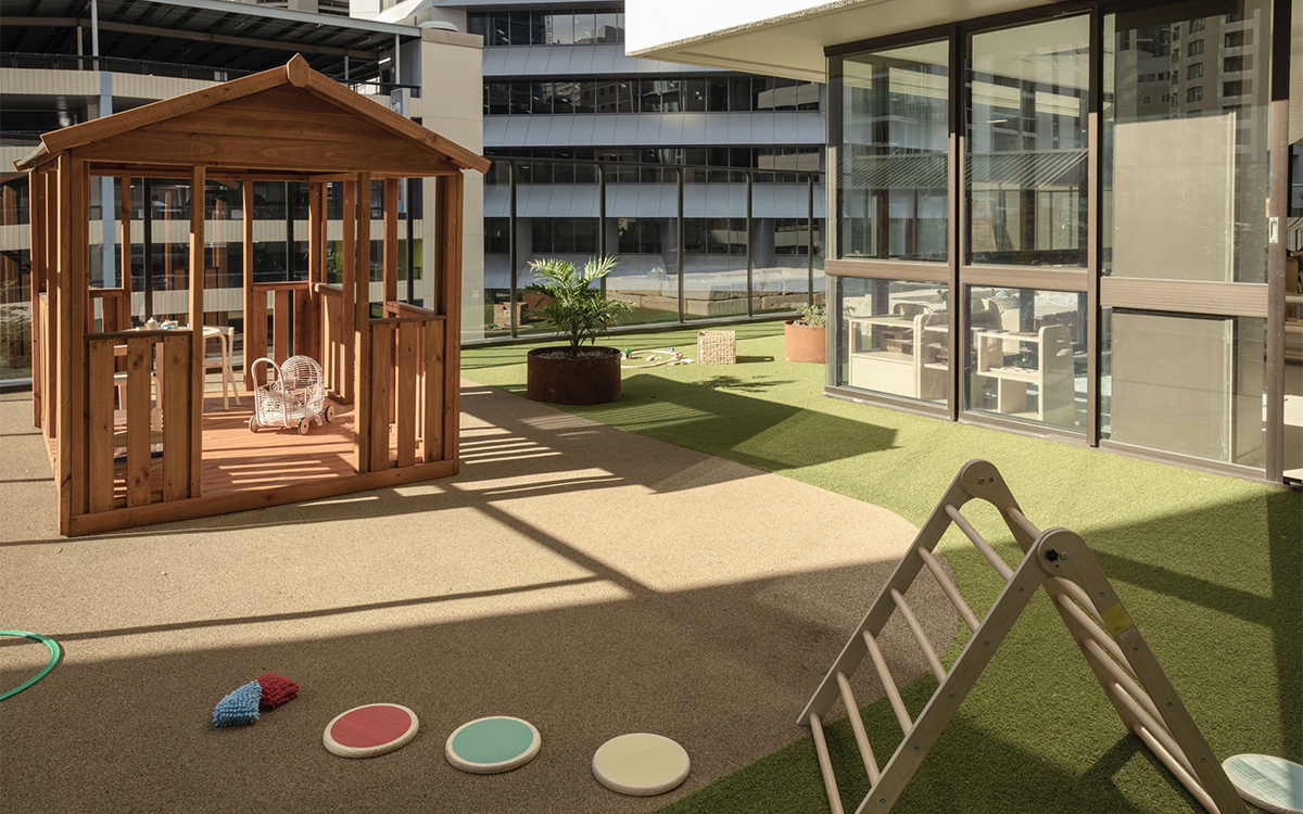 Outdoor rooftop playground at HEI Schools with playhouse and nature play.
