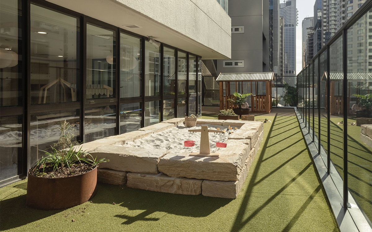 Rooftop sandpit and outdoor play area at HEI Schools with natural play elements and city views.