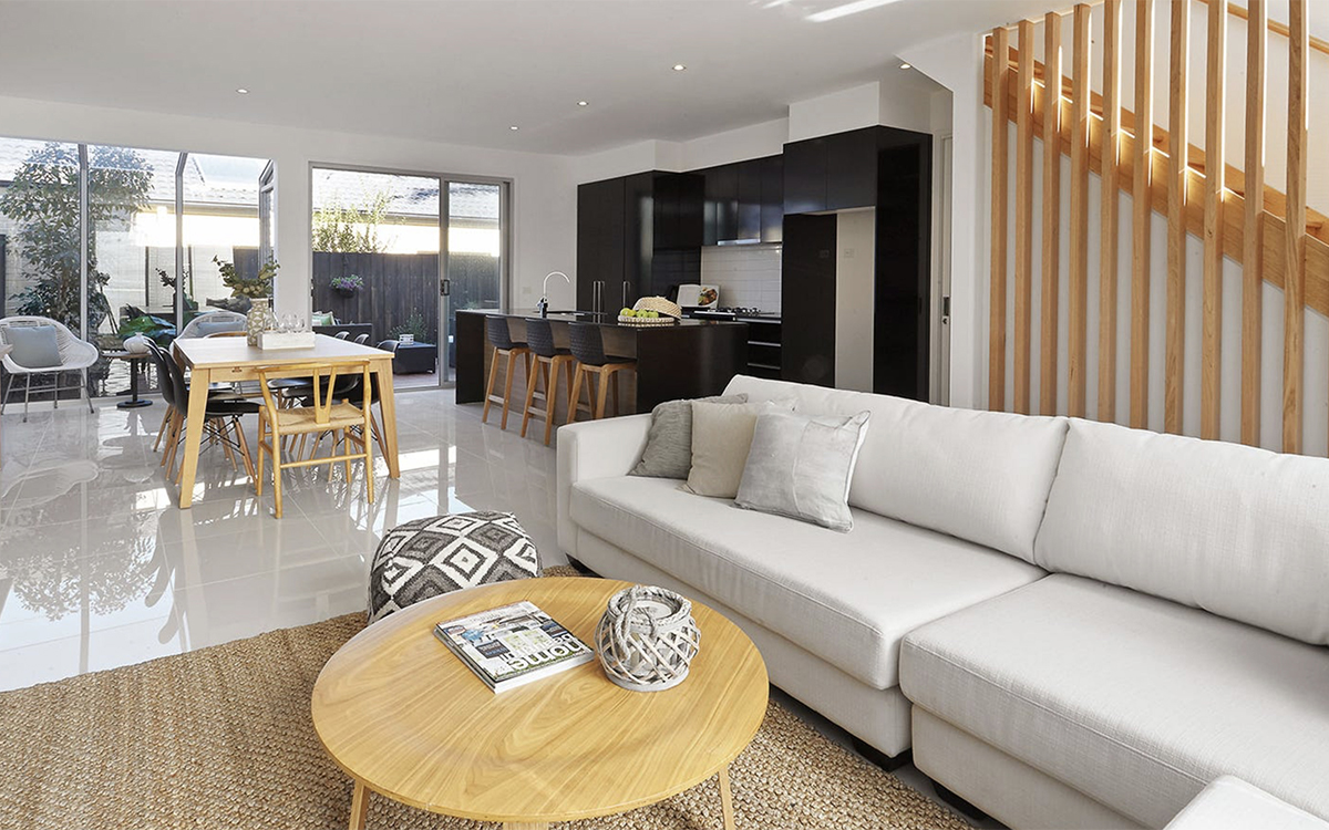 Open-plan living, dining and kitchen area with island bench, staircase screen and sliding doors to an outdoor courtyard.