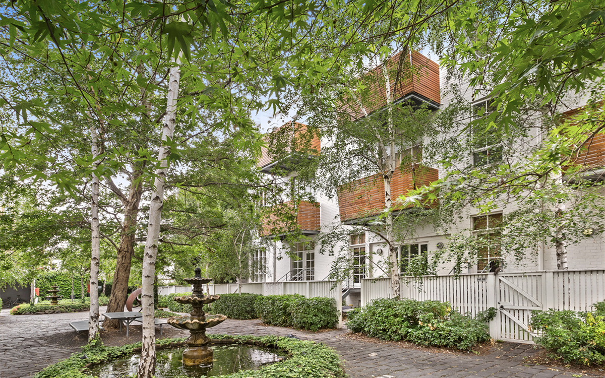 Landscaped communal courtyard with mature trees, fountain and apartment buildings at Tullo Place.