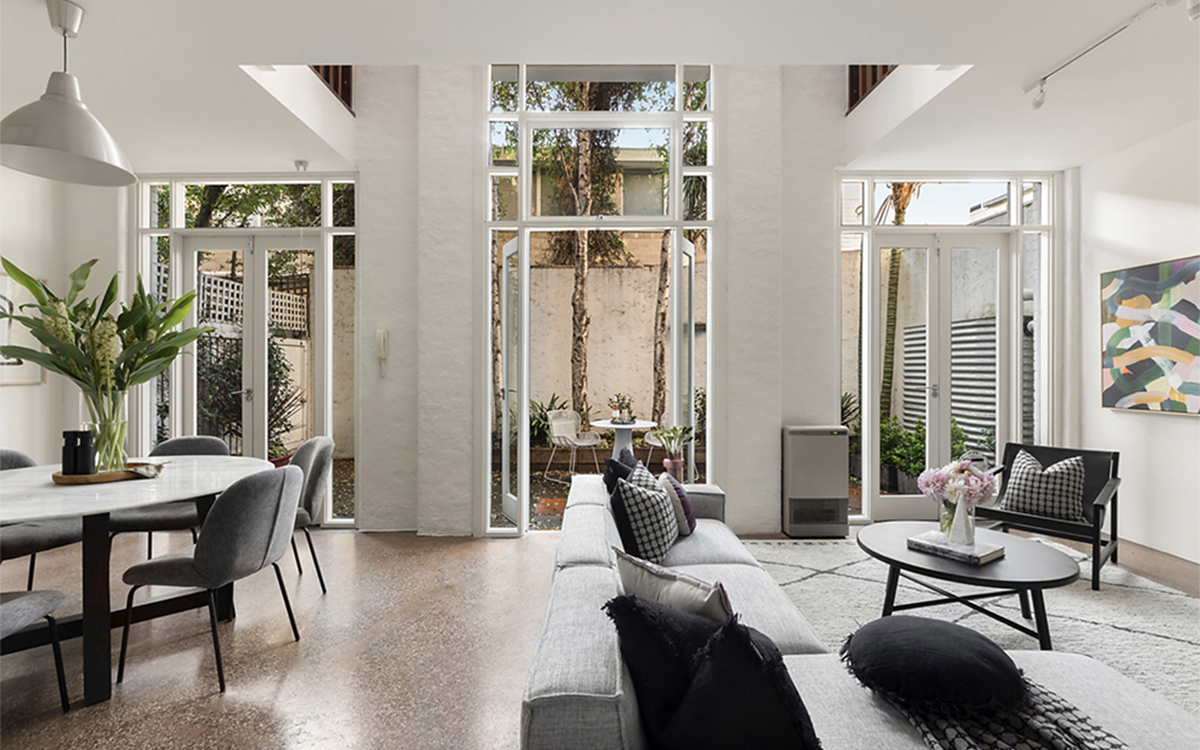 Open-plan living and dining area with double-height windows and private courtyard at Tullo Place.