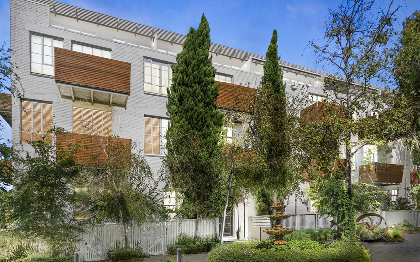 Landscaped communal gardens at Tullo Place featuring apartment buildings, mature trees and central fountain.