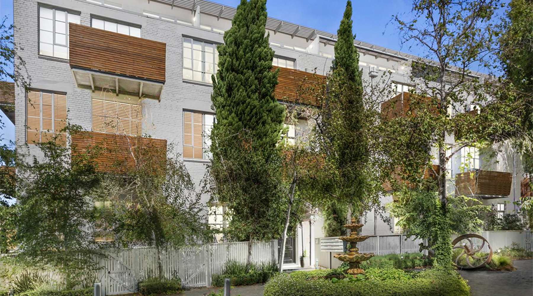 Courtyard view of Tullo Place apartment development with landscaped gardens, mature trees and balconies.
