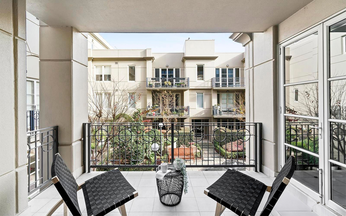 Apartment balcony overlooking a landscaped central courtyard with surrounding residences.