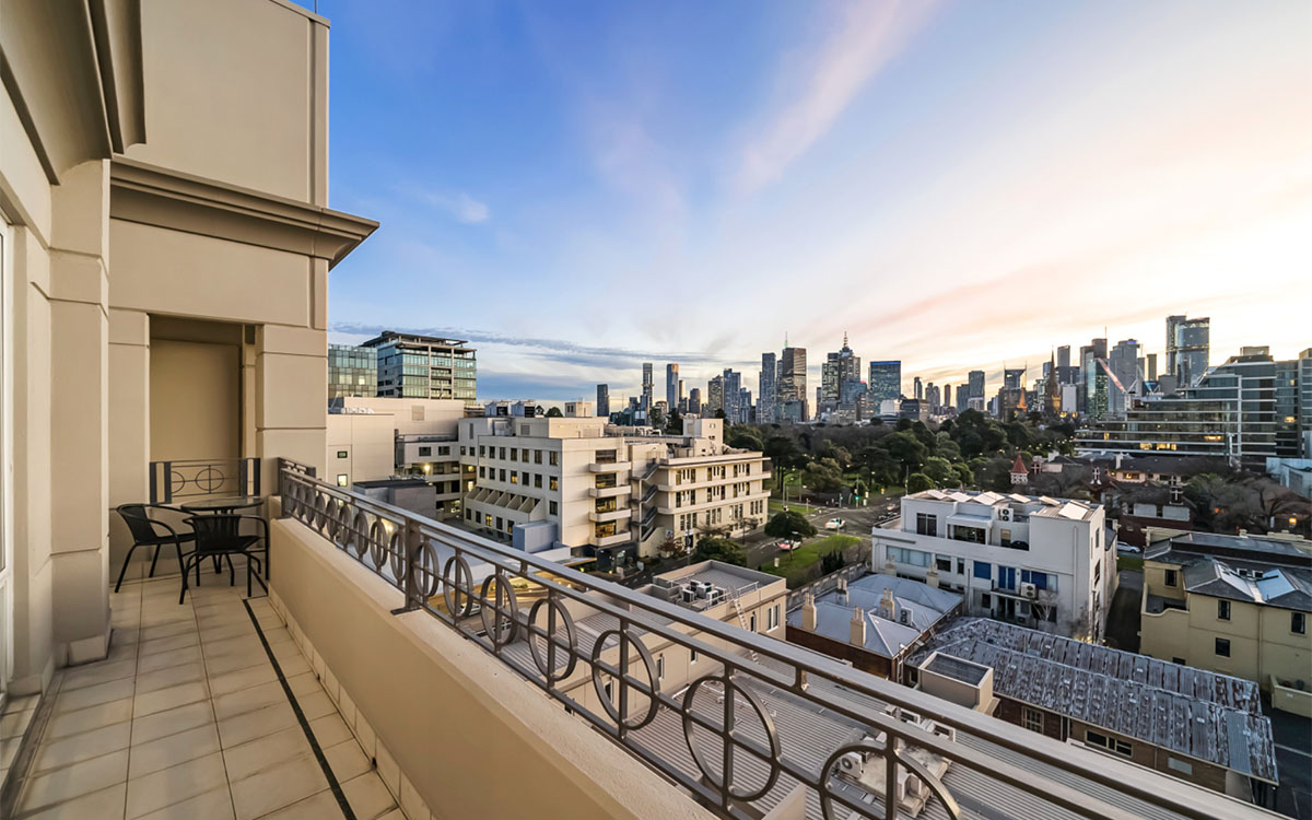 Apartment balcony with outdoor seating overlooking the Melbourne city skyline.